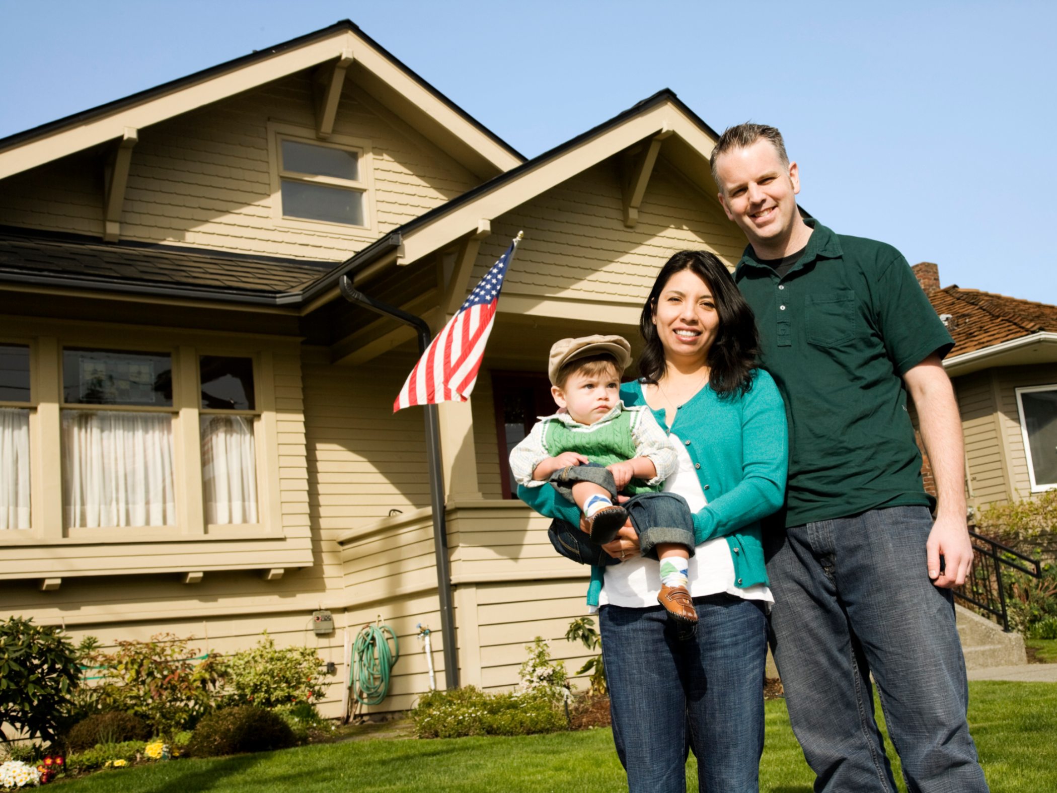 Family of three standing outside house