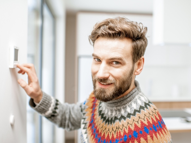 Man at home adjusting thermostat