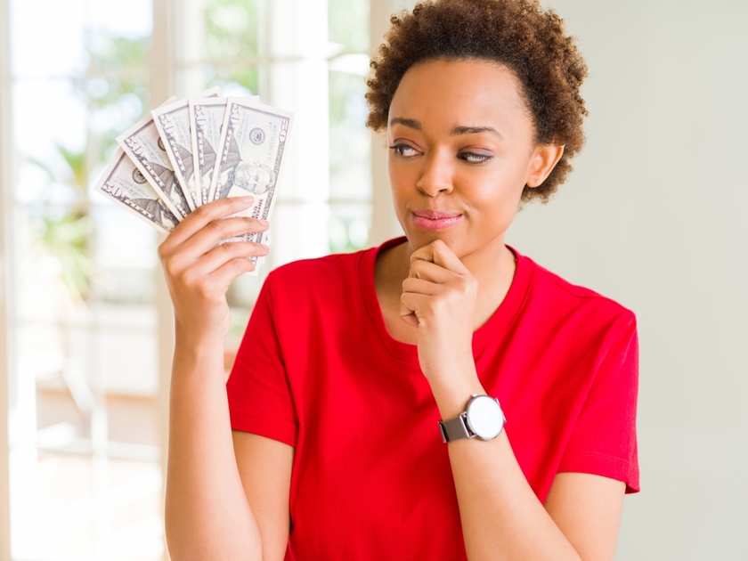 Woman holding money and thinking