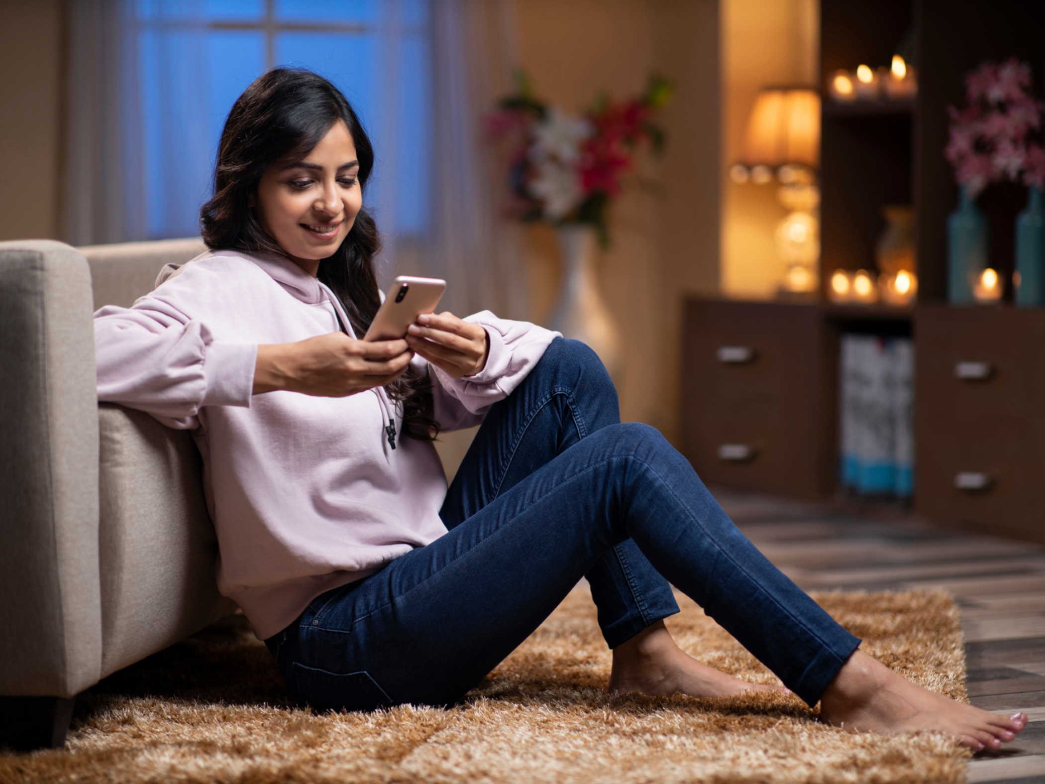 Woman at home in the evening using smartphone