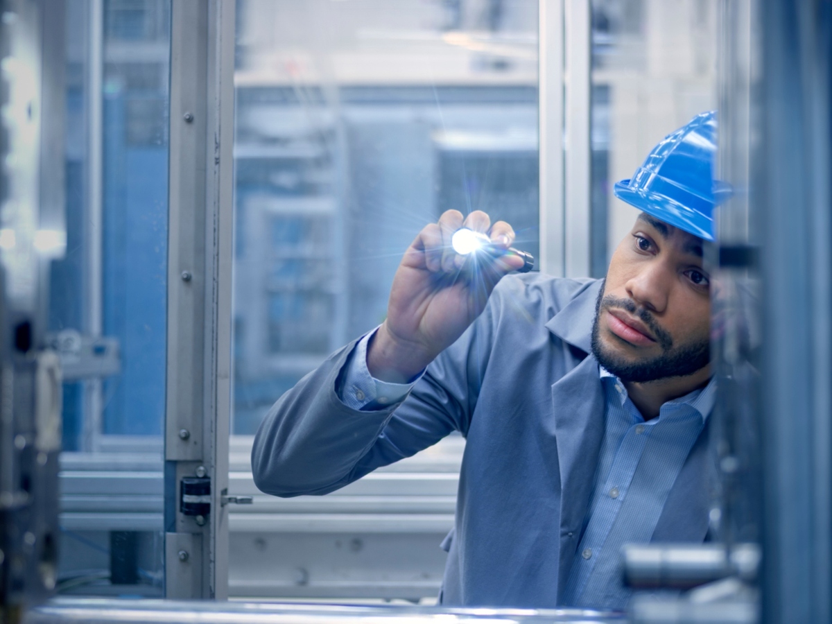 Engineer with flash light looking at machinery