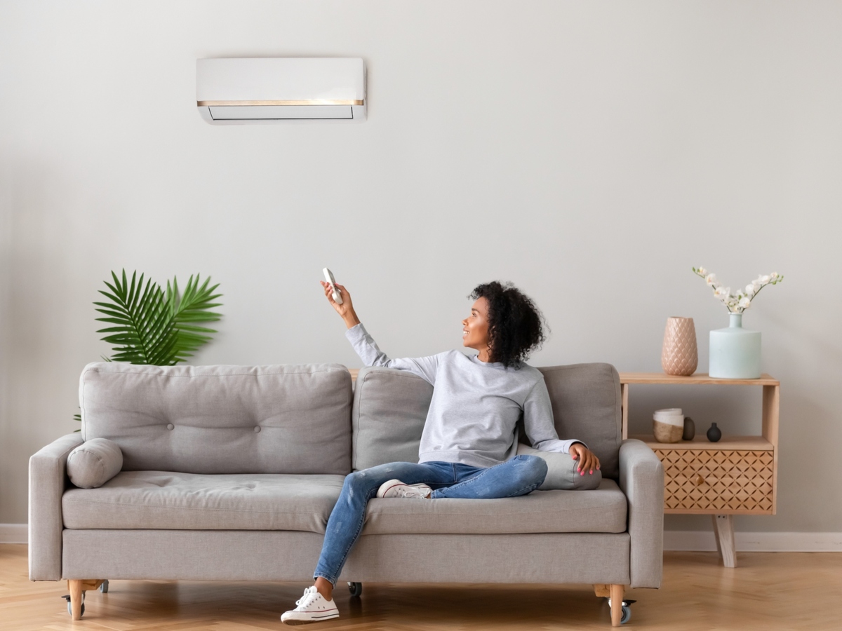 Woman using remote control for heat pump