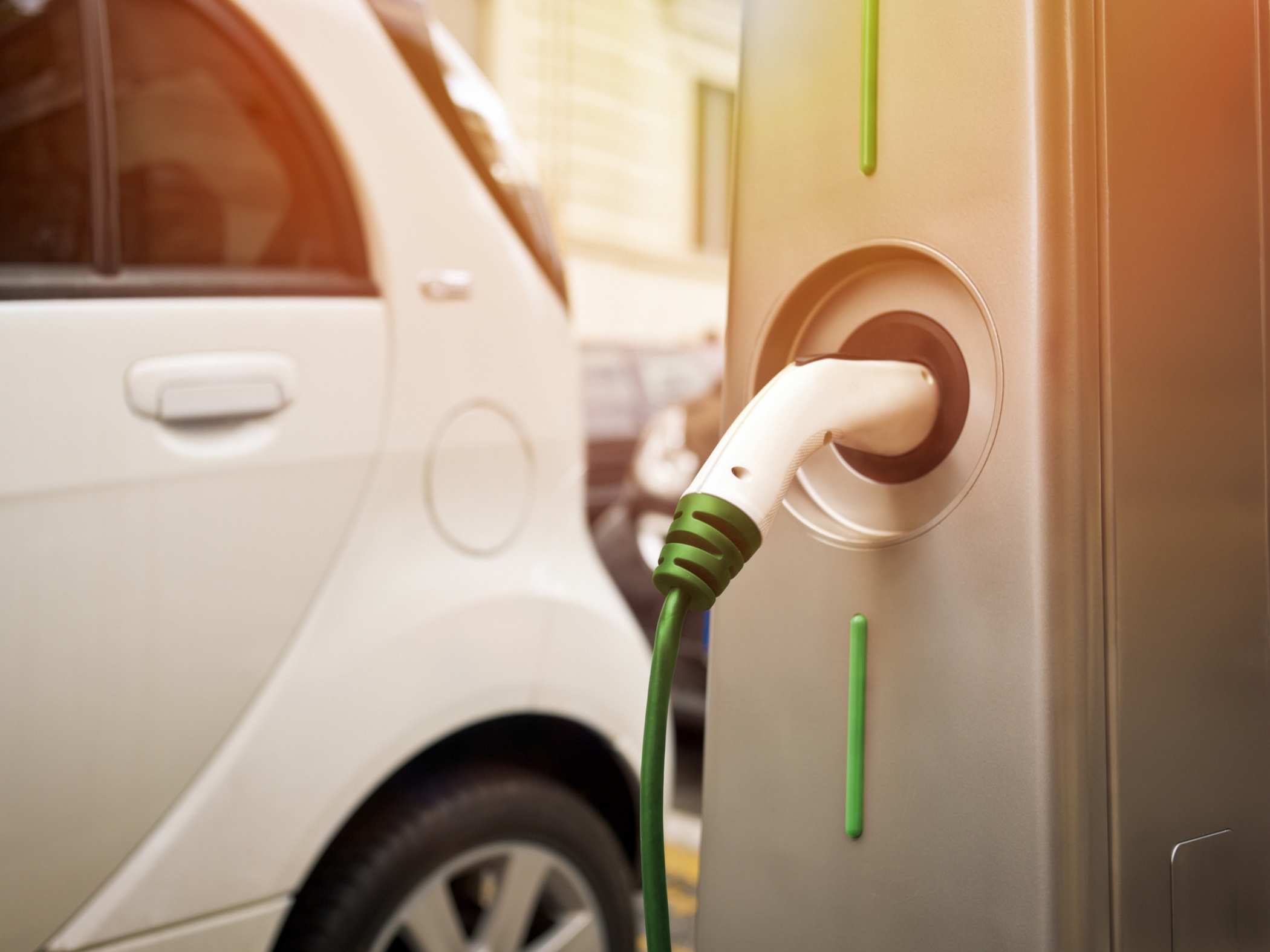 an electric vehicle charging station with an electric vehicle charging in the background