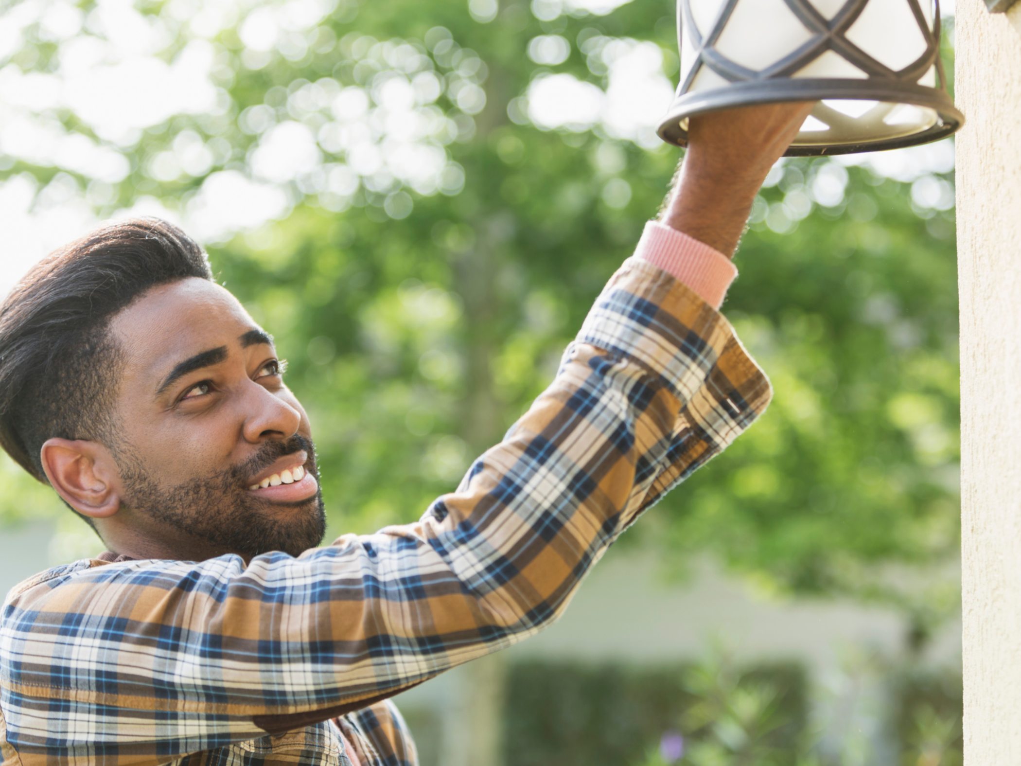 Man outside house changing lightbulb