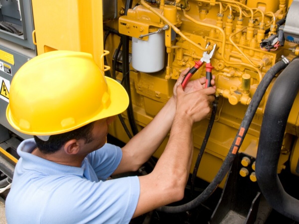 Worker in hardhat performing maintenance on generator