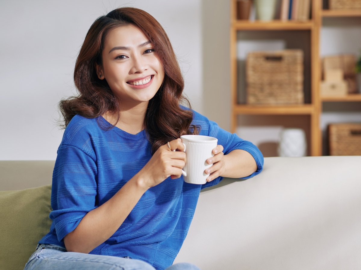 Woman sitting on couch drinking coffee