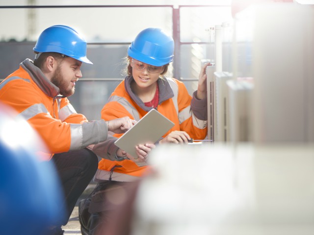 HVAC workers using mobile device on rooftop
