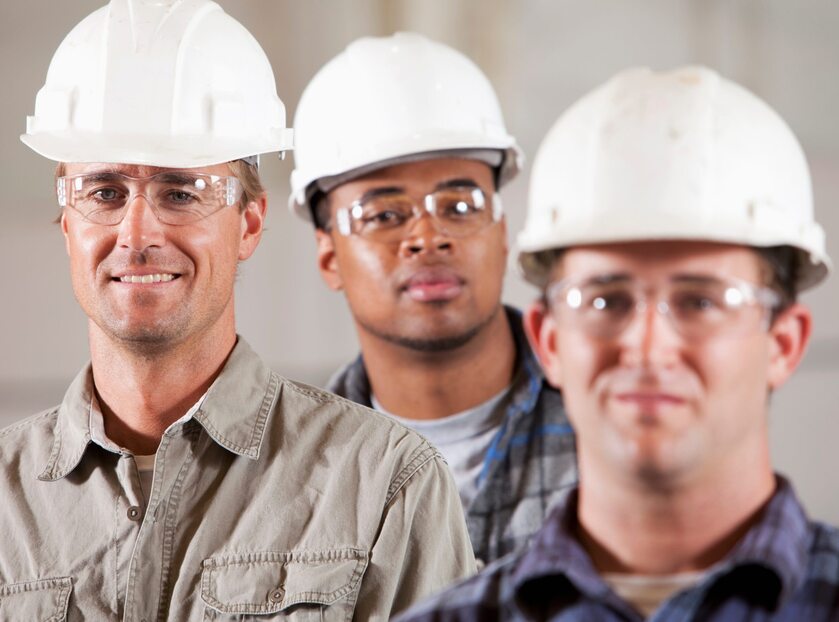 Three workers in hardhats and safety glasses